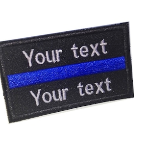 Op de afbeelding: Zwarte geborduurde patch met een blauwe streep en de tekst "Your text" boven en onder.