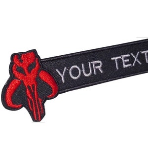 May include: Black and red embroidered patch with a Mandalorian symbol and the text "YOUR TEXT" in white.