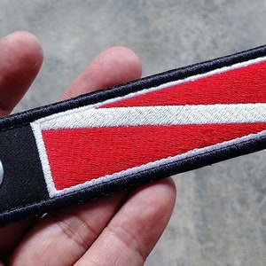 May include: A black and red scuba diving flag keyring with a silver ring.