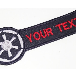 May include: Black and white embroidered patch with the Star Wars Imperial symbol. A black rectangular patch with the text "YOUR TEXT" in red embroidery.