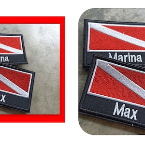 May include: Two embroidered patches featuring a red and white scuba diving flag design. The patches have black borders and the names "Marina" and "Max" are embroidered on them. A black patch is also shown, labelled "black side".