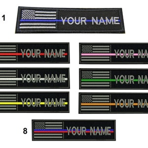 Puede incluir: Ocho parches bordados con un diseño de bandera estadounidense y una fina franja de color a través de la bandera. Cada parche tiene el texto "YOUR NAME" debajo de la bandera. Las franjas son azules, rojas, rosas, blancas, verdes, amarillas, naranjas y rojas y azules.