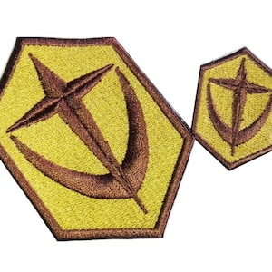 Peut inclure: Deux patchs brodés en forme hexagonale avec un motif d'étoile et de croissant de lune brun sur fond jaune.