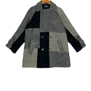 May include: A black and grey patchwork double-breasted coat with a collar and pockets.