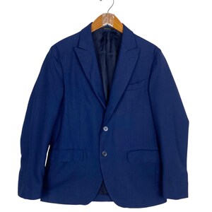 May include: A navy blue blazer with a two-button closure, notched lapels, and two front pockets. The jacket is hanging on a wooden hanger against a white background. The blazer is a classic style.