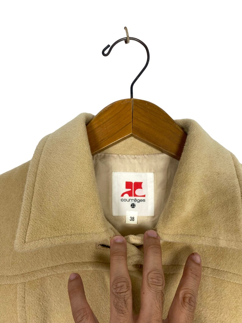 May include: A beige wool coat with a large red label that says "Courr&egrave;ges" and a size 38.