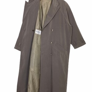 May include: A long, gray trench coat with a double-breasted closure and a label that reads "Isante".