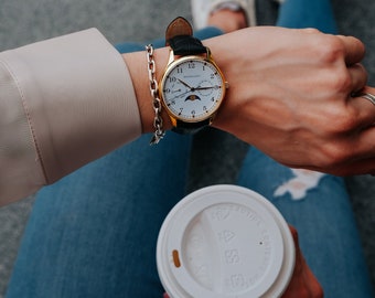 Reloj dorado para mujer de 36 mm con correa de piel negra.