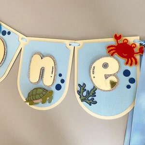 Uno striscione per seggiolone sotto il mare. Ghirlanda per il primo compleanno. Decorazioni per feste. Creatura sottomarina, bambino