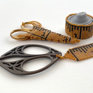 May include: A set of three gold and black beaded measuring tapes, including a rolled-up tape and two straight tapes, and a pair of silver-colored scissors.