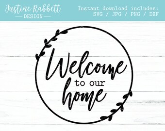 Puede incluir: Un diseño circular en blanco y negro con las palabras "Welcome to our home" en una fuente de escritura. El diseño incluye un borde decorativo de hojas y el texto "Justine Rabbett Design".