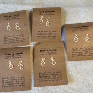 May include: Five brown cardboard cards labeled Reform Initials, each featuring two white embroidered letter S monograms. The text reads: Wash like Linen, Easy to Embroider, Can be used in single letters or combined as Monograms.