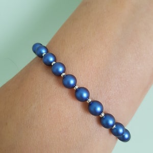 May include: A blue beaded bracelet with silver accents. The bracelet is made of round beads with a metallic finish.
