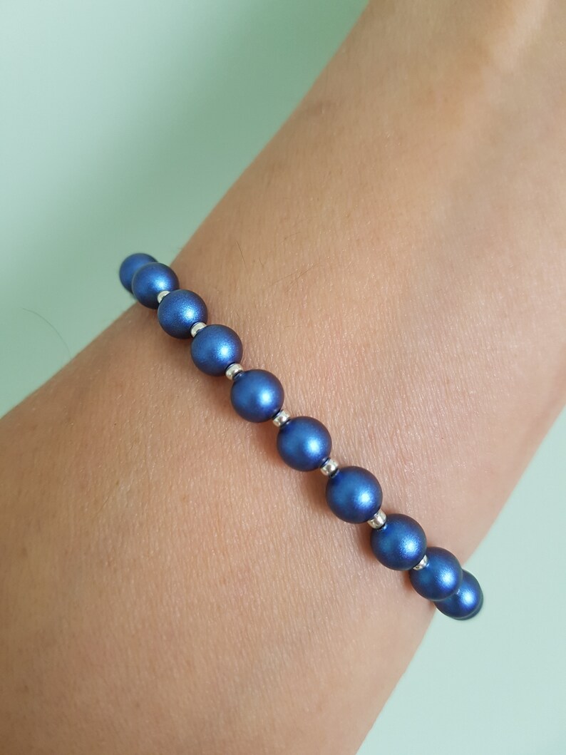 May include: A blue beaded bracelet with silver accents. The bracelet is made of round beads with a metallic finish.