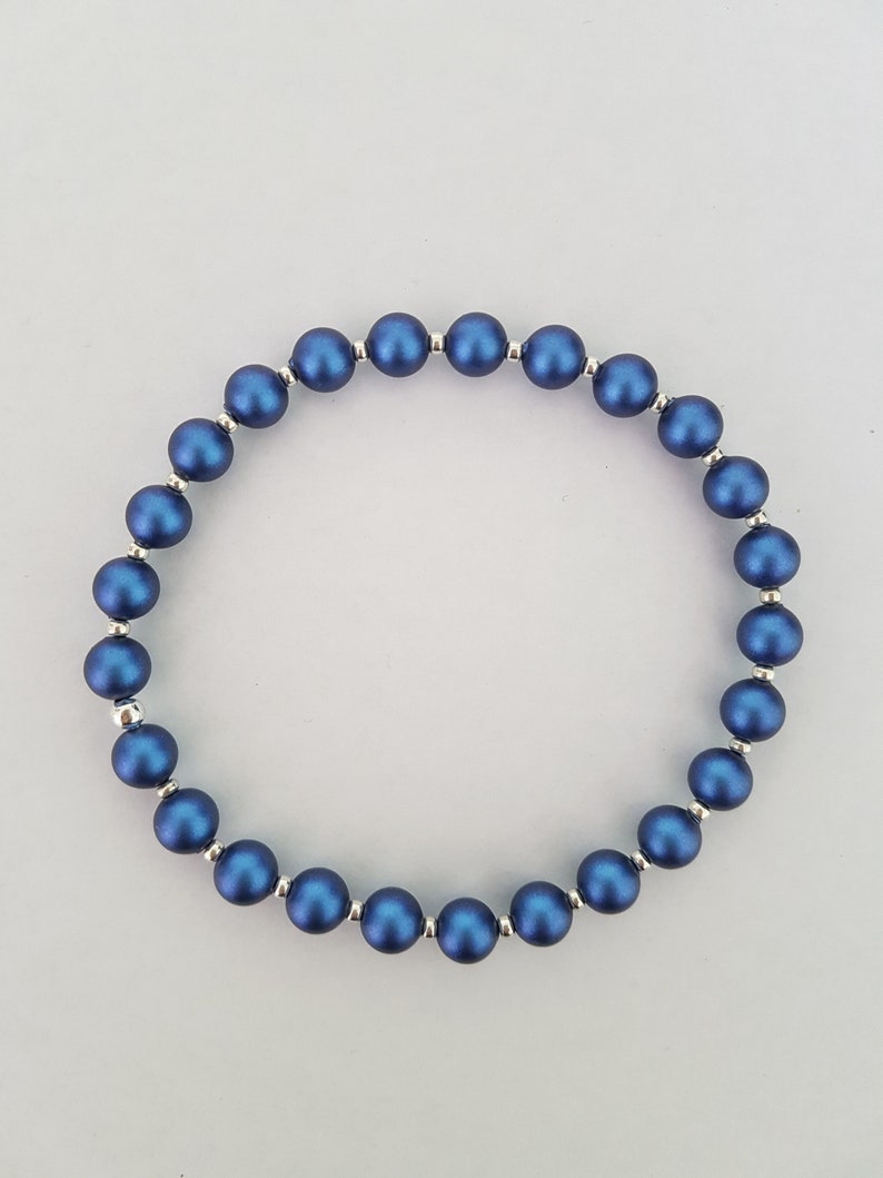 May include: A blue beaded bracelet with silver accents. The beads are round and have a matte finish.