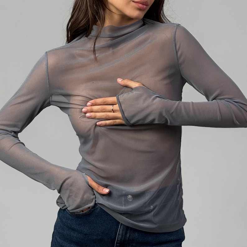 May include: A grey sheer long-sleeved shirt with a mock neck and thumbholes.