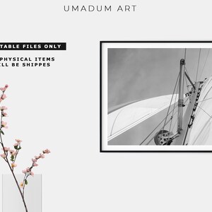 May include: Black and white photograph of a sailboat's rigging and sail. The image is taken from a low angle, looking up at the sail.