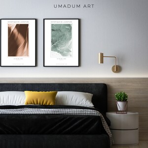 May include: Two framed abstract art prints with the text "Esthetique de l'Aventure" and "La Vie de la Mer" hanging on a white wall above a black headboard bed with a yellow pillow and a white nightstand with a potted plant.