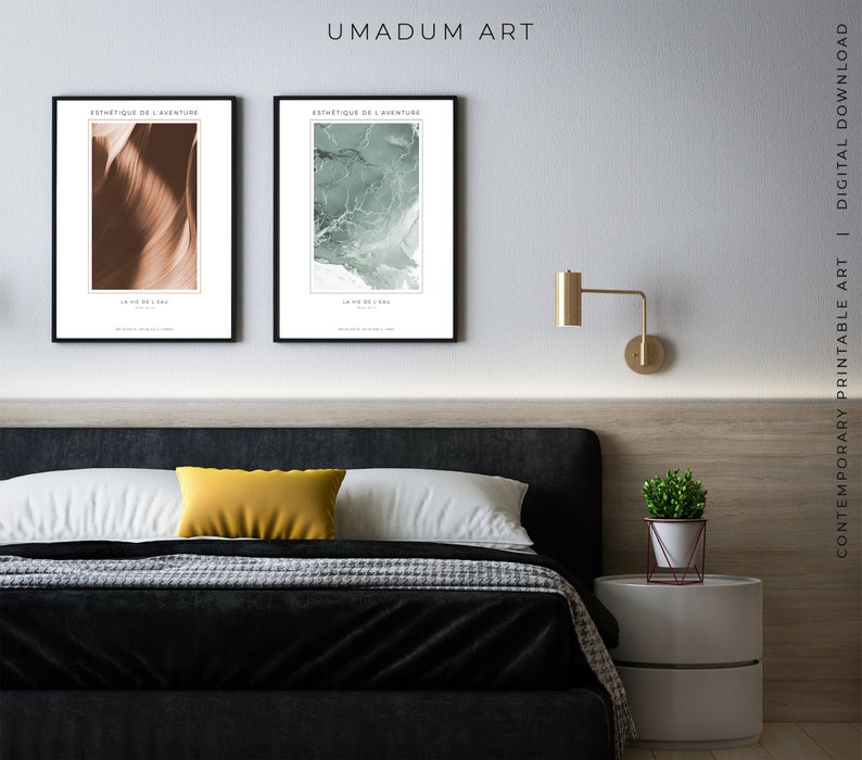 May include: Two framed abstract art prints with the text "Esthetique de l'Aventure" and "La Vie de la Mer" hanging on a white wall above a black headboard bed with a yellow pillow and a white nightstand with a potted plant.