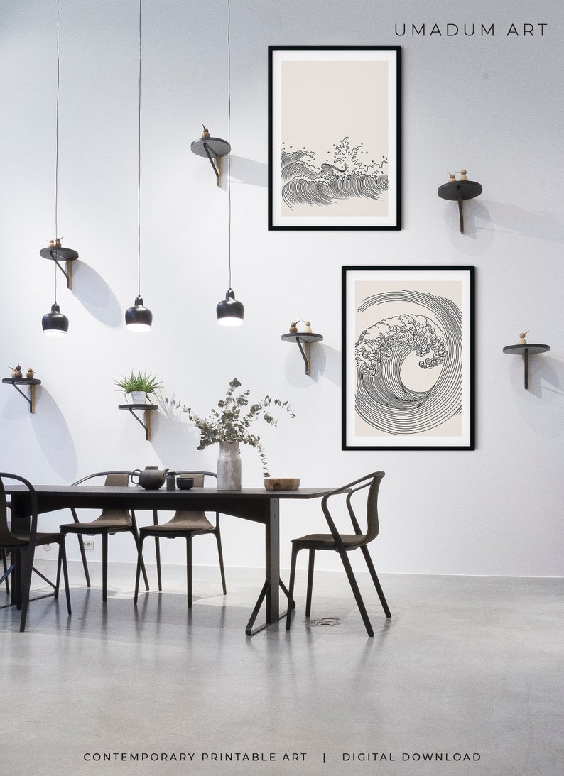 K&ouml;nnte beinhalten: Zwei schwarze gerahmte Drucke von Strichzeichnungen von Wellen auf cremefarbenem Hintergrund. Die Drucke h&auml;ngen an einer wei&szlig;en Wand in einem Esszimmer mit einem schwarzen Tisch und St&uuml;hlen. Der Text "UMADUM ART" befindet sich in der oberen rechten Ecke des Bildes. Der Text "CONTEMPORARY PRINTABLE ART | DIGITAL DOWNLOAD" befindet sich am unteren Rand des Bildes.