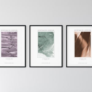 May include: Three framed prints with black frames and white mats. Each print features a different abstract design in shades of purple, green, and brown. The text "ESTHETIQUE DE L'AVENTURE" and "LA VIE DE L'EAU" is printed on each print.