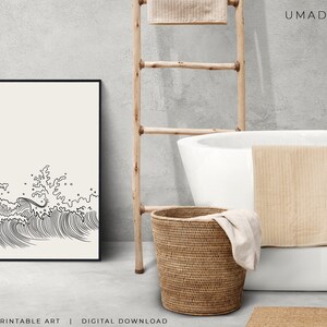 K&ouml;nnte beinhalten: Schwarz-wei&szlig;-Linienkunst-Druck von brechenden Wellen. Der Druck ist gerahmt und h&auml;ngt an einer Wand in einem Badezimmer mit einer wei&szlig;en Badewanne, einer Holzleiter und einem Weidenkorb.