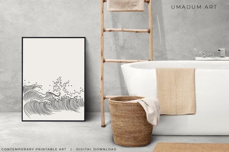 K&ouml;nnte beinhalten: Schwarz-wei&szlig;-Linienkunst-Druck von brechenden Wellen. Der Druck ist gerahmt und h&auml;ngt an einer Wand in einem Badezimmer mit einer wei&szlig;en Badewanne, einer Holzleiter und einem Weidenkorb.