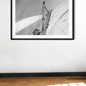 May include: Black and white photograph of a sailboat's mast and rigging against a cloudy sky.