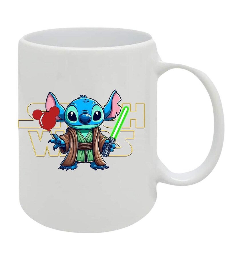 May include: White ceramic mug featuring a cartoon character resembling Stitch from Lilo & Stitch, dressed as Yoda from Star Wars. The character holds a green lightsaber and red balloons. The Star Wars logo is in gold.