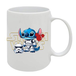 May include: White ceramic mug featuring a blue cartoon character with large eyes, wearing a white stormtrooper outfit and holding a red balloon. The mug has the words "STAR WARS" in gold lettering.