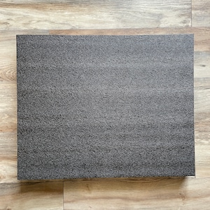 May include: A black rectangular foam pad with a textured surface.