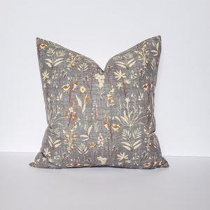 May include: A gray throw pillow with a floral pattern in shades of white, yellow, and orange.
