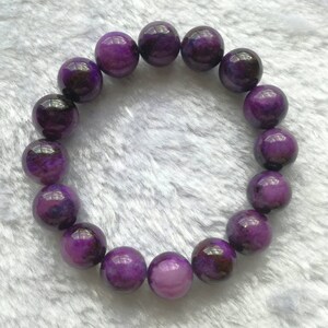 May include: A purple gemstone bracelet with round beads. The beads have a light purple and dark purple marbled pattern.