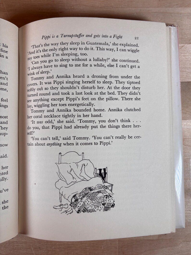 Puede incluir: Un libro abierto con texto y una ilustraci&oacute;n en blanco y negro de una cama con una colcha de retazos, zapatos y un par de calcetines. El texto dice "Pippi es un Turnupstuffer y se pelea."