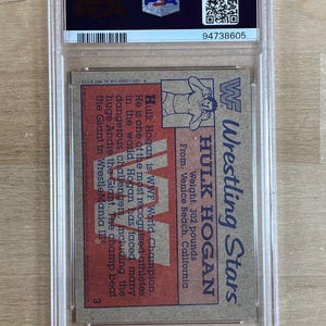 May include: A vintage WWF Wrestling Stars trading card featuring Hulk Hogan, encapsulated in a protective case. The card displays Hogan's image, weight (302 pounds), and location. The text on the card describes Hogan's achievements.