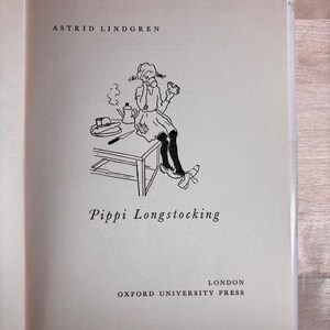 May include: The title page of the book Pippi Longstocking by Astrid Lindgren, published by Oxford University Press in London. It features a black ink line drawing of a character sitting on a table with a teapot, plate, and knife.