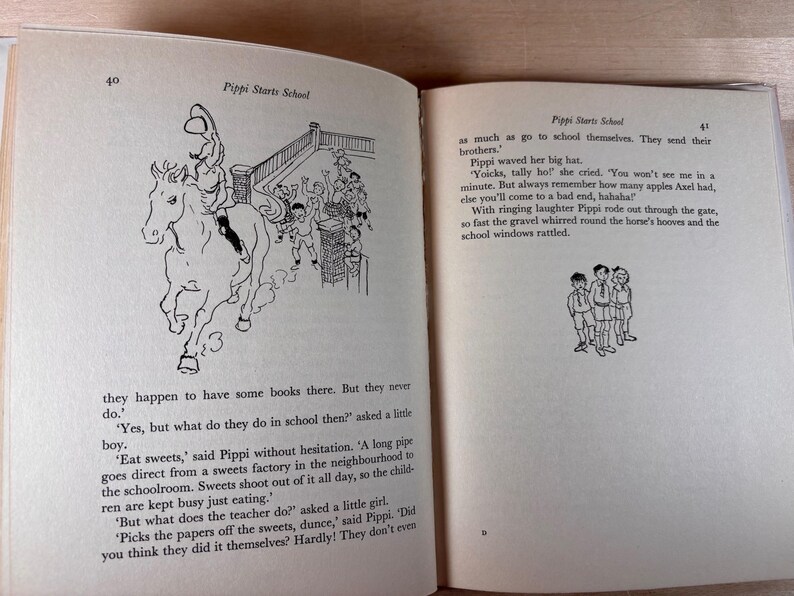 Puede incluir: Un libro abierto con ilustraciones y texto en blanco y negro. Una ilustraci&oacute;n muestra a una persona montada a caballo, con ni&ntilde;os cerca. El texto dice "Pippi Starts School". El libro est&aacute; abierto en dos p&aacute;ginas.