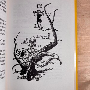 May include: A black and white book illustration depicting three children in a natural setting. One child stands near a large, gnarled tree, another climbs the trunk, and a third stands in the background with a small object floating above them.