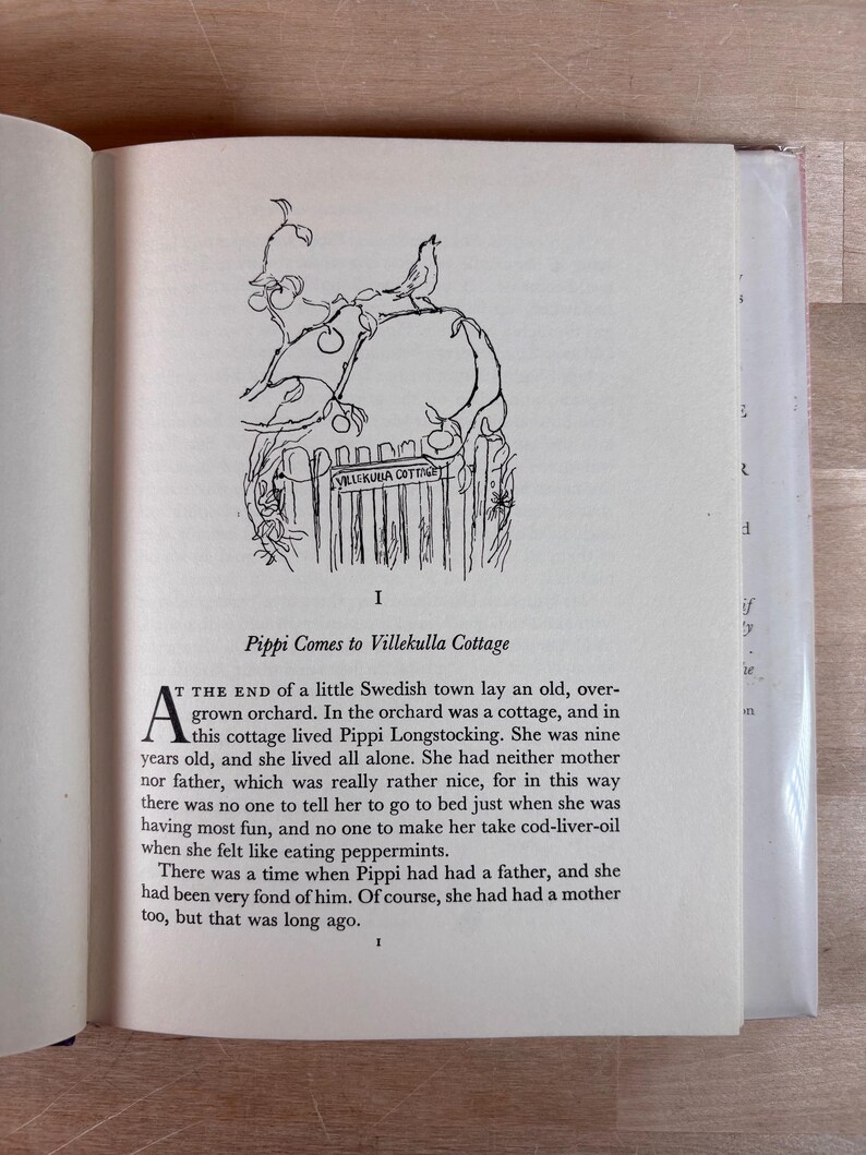 Puede incluir: P&aacute;gina de libro abierta con texto y una ilustraci&oacute;n en blanco y negro. La ilustraci&oacute;n muestra un p&aacute;jaro posado en una rama sobre una valla con el texto "VILLEKULLA COTTAGE". El texto de la p&aacute;gina es el comienzo de una historia.