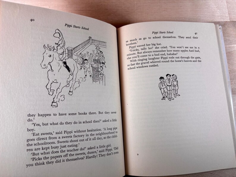 May include: An open book titled Pippi Starts School with pages 40 and 41 visible. The text describes Pippi Longstocking, featuring black and white line illustrations of a person riding a horse and a group of three children standing together.