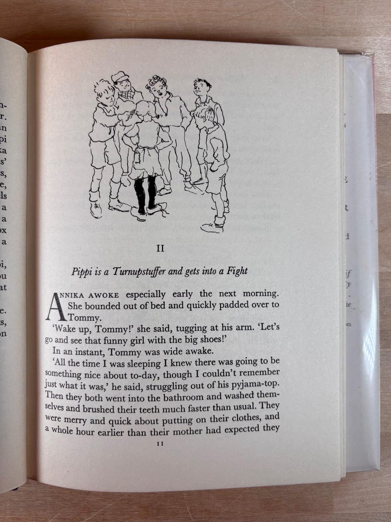 Puede incluir: Libro abierto con texto y una ilustraci&oacute;n en blanco y negro de ni&ntilde;os. La ilustraci&oacute;n muestra un grupo de ni&ntilde;os. El texto dice "Pippi is a Turnupstuffer and gets into a Fight".