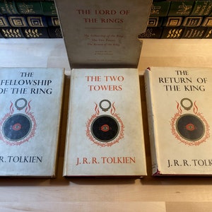 May include: Three hardcover books, The Fellowship of the Ring, The Two Towers, and The Return of the King, all by J.R.R. Tolkien. The books are part of the Lord of the Rings trilogy and feature a black and red eye symbol on the cover.