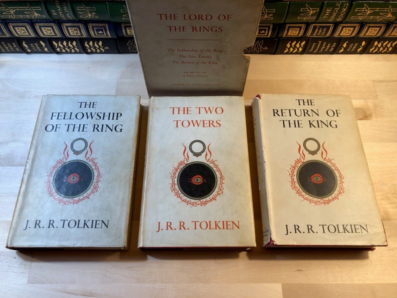 May include: Three hardcover books, The Fellowship of the Ring, The Two Towers, and The Return of the King, all by J.R.R. Tolkien. The books are part of the Lord of the Rings trilogy and feature a black and red eye symbol on the cover.