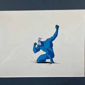 May include: A blue superhero character with a bug-like head is crouched in a fighting pose. The character is drawn in a cartoon style and is set against a white background.