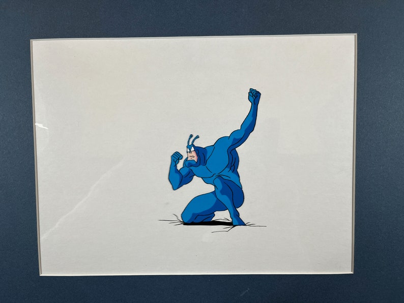 May include: A blue superhero character with a bug-like head is crouched in a fighting pose. The character is drawn in a cartoon style and is set against a white background.