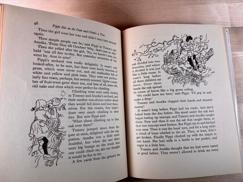 May include: An open hardcover book featuring black and white illustrations and printed text from the story Pippi Sits on the Gate and Climbs a Tree. The pages contain narrative paragraphs and line drawings of children climbing in an oak tree.