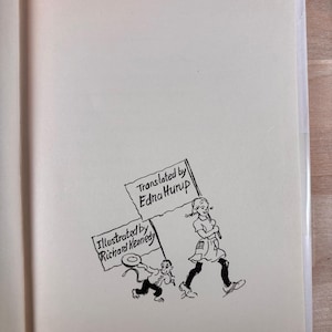 May include: A book page featuring a black ink line drawing of a person and a small creature walking together. The person carries a sign reading Translated by Edna Hurup, while the creature carries a sign reading Illustrated by Richard Kennedy.