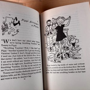 May include: An open book page featuring black and white illustrations of a character with braided hair scrubbing a floor. The text includes the chapter title Pippi Arranges a Picnic and narrative paragraphs describing Pippi, Tommy, and Annika.