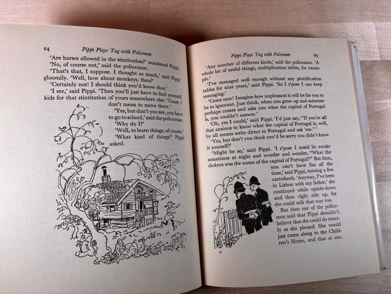 May include: An open book titled Pippi Plays Tag with Policemen, featuring two pages of printed text and black and white line illustrations. The left page shows a house under a tree, and the right page depicts two policemen standing by a fence.