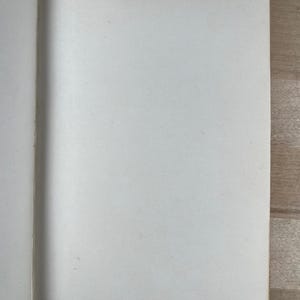 May include: Open notebook with blank white pages. Handwritten text in the upper right corner reads "6 vols 140". The notebook is open on a light-colored wooden surface.